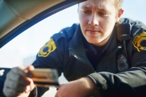 A police officer looking at a drivers’ license at a DUI checkpoint in Columbus